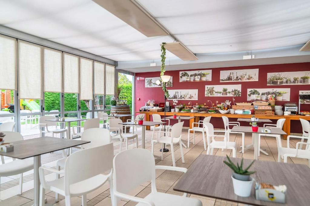 un restaurant avec des tables et des chaises blanches et des murs rouges dans l'établissement Domino Suite Hotel & Residence, à Lido di Jesolo