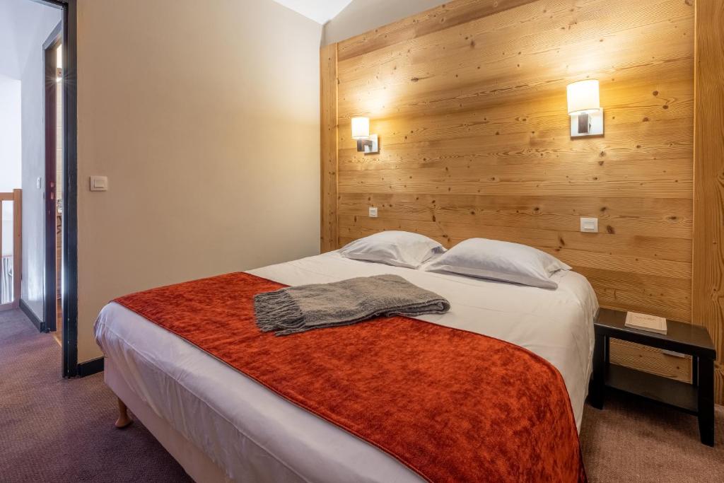 une chambre avec un grand lit avec un mur en bois dans l'établissement Résidence Pierre & Vacances Le Quartz, à Belle Plagne