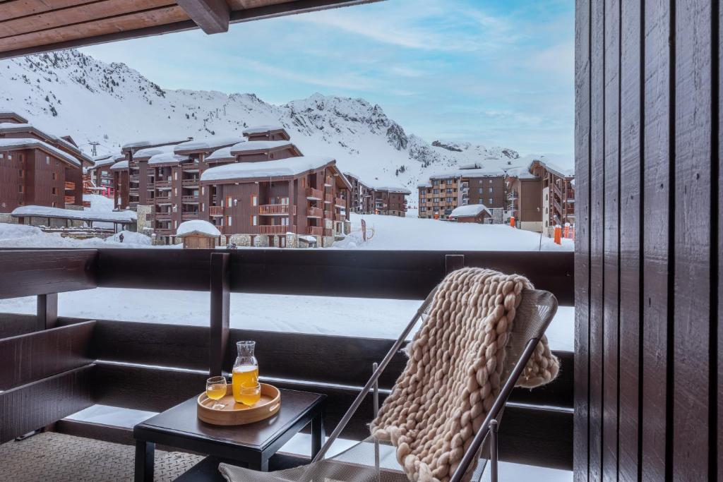 une chaise sur un balcon avec vue sur une montagne enneigée dans l'établissement Résidence Pierre & Vacances Le Quartz, à Belle Plagne