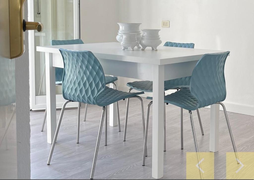 une table avec quatre chaises et une table blanche avec une table dans l'établissement CASA MAJOR Hotel & Appartamenti CERVIA, à Cervia
