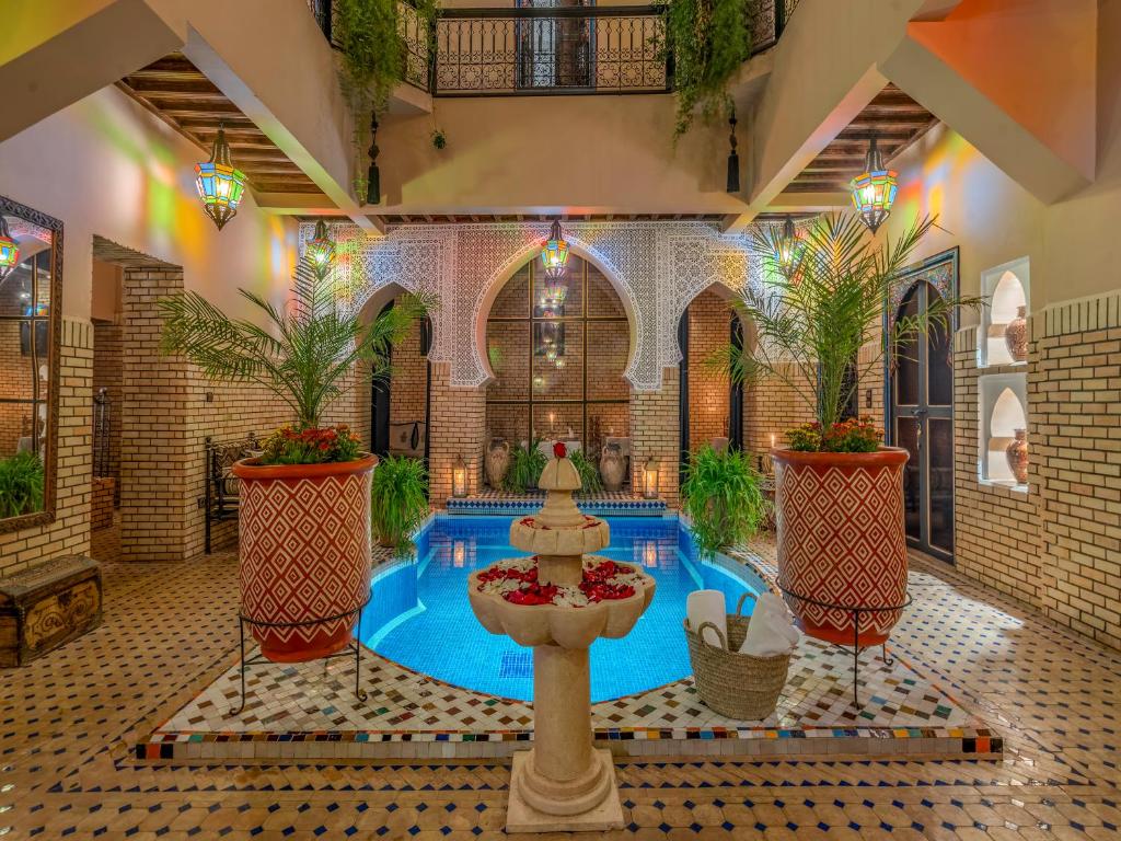 une piscine au milieu d'un bâtiment avec une fontaine dans l'établissement Riad Irhalne, à Marrakech