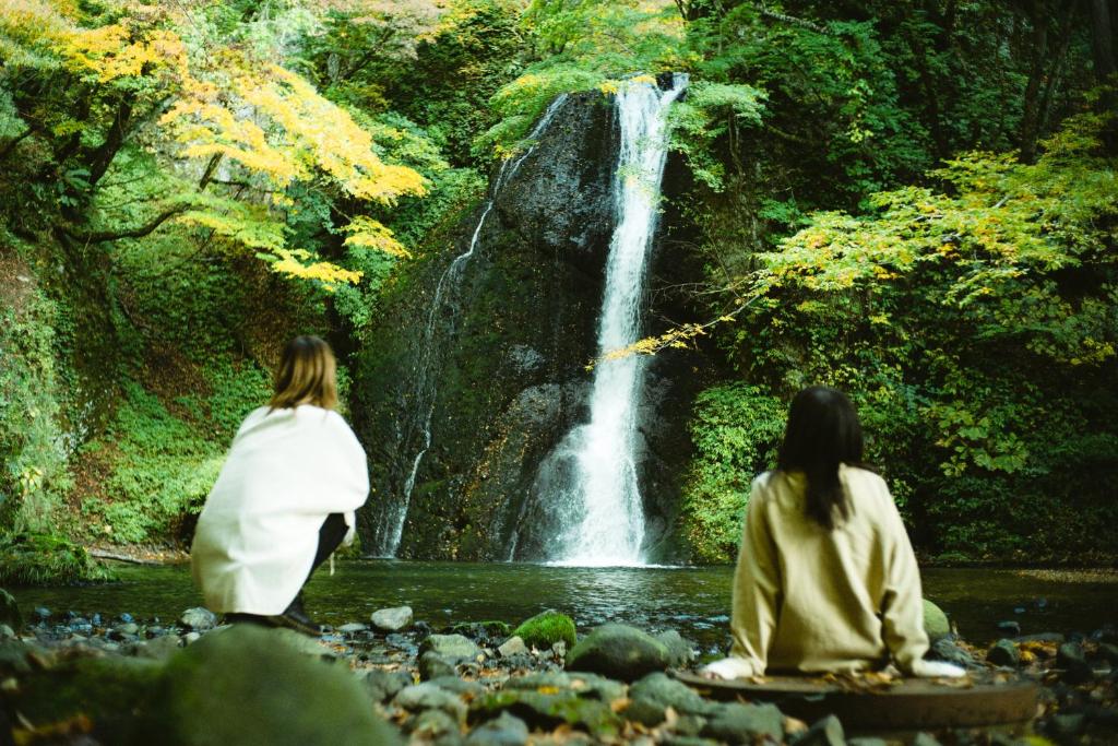 deux femmes assises devant une cascade dans l'établissement Hotel Yutoria Fujisato, à Fujisato