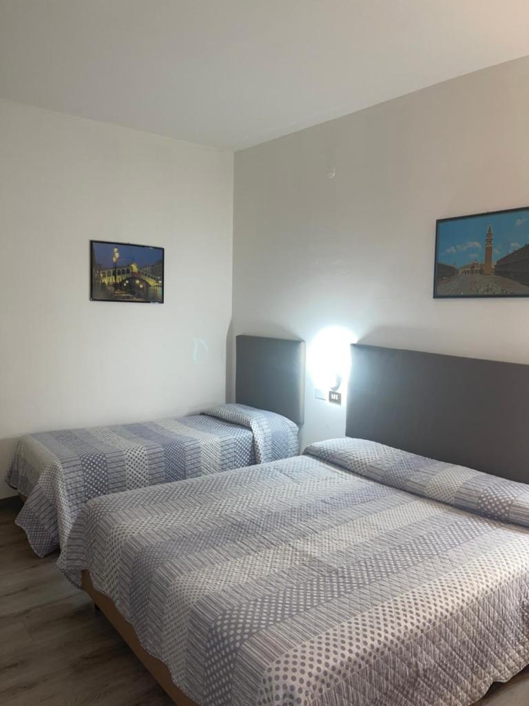 deux lits dans une chambre aux murs blancs dans l'établissement Hotel San Marco, à Lido di Jesolo 18 autres photos