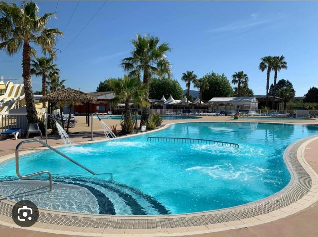 une grande piscine avec des palmiers dans un complexe hôtelier dans l'établissement Mobil home le Montourey, à Fréjus