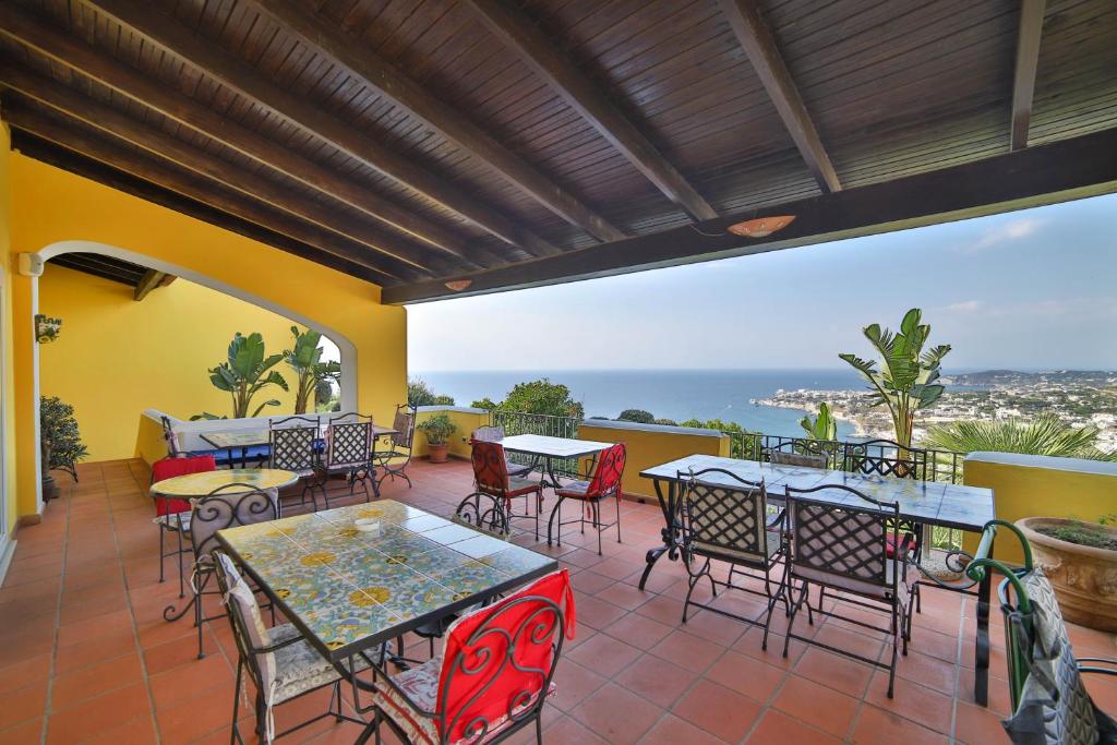 un patio avec tables et chaises et vue sur l'océan dans l'établissement Sweetposeidon, à Ischia