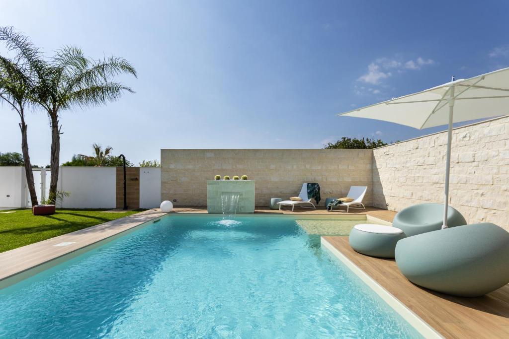 une piscine avec deux chaises et un parasol dans l'établissement Villa Amugea - IsulaTravel, à Ispica