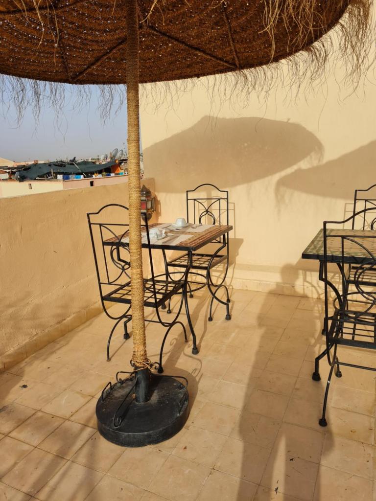 - une table et des chaises sous un parasol sur la terrasse dans l'établissement Riad Dantella, à Marrakech