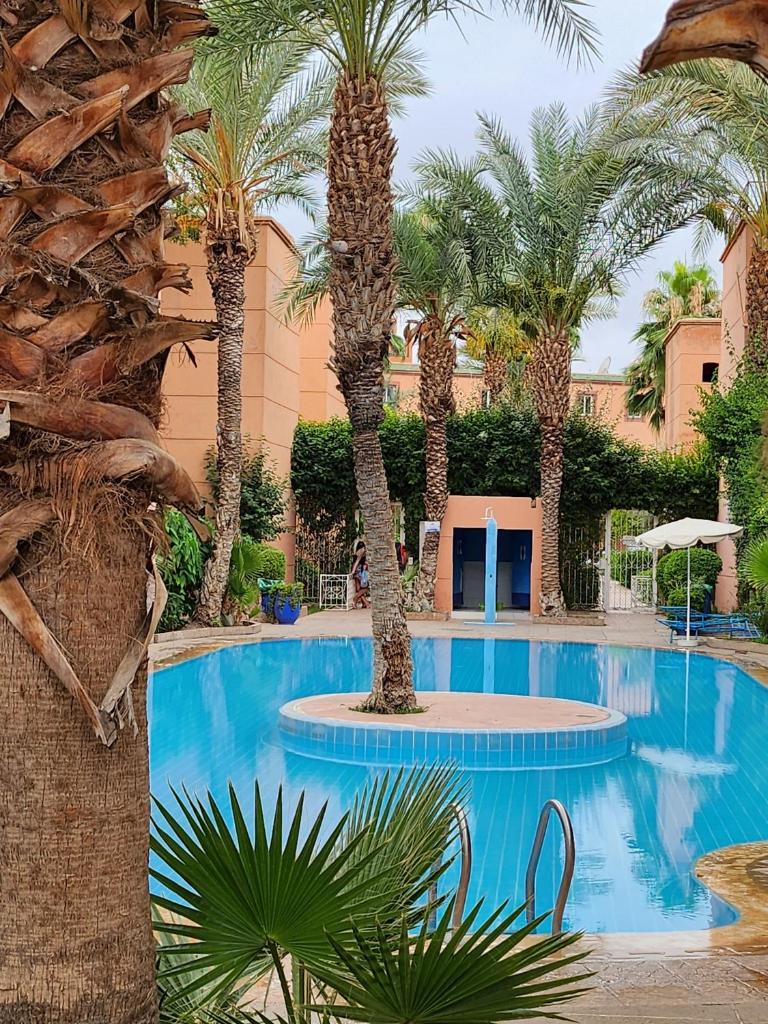 une piscine avec des palmiers dans un complexe hôtelier dans l'établissement Riad with 3 Swimming Pools, à Marrakech