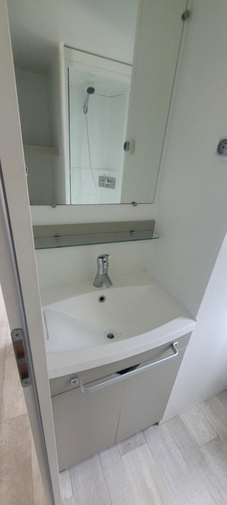 une salle de bain blanche avec un lavabo et un miroir dans l'établissement Camping le Neptune 4 étoiles, à Argelès-sur-Mer