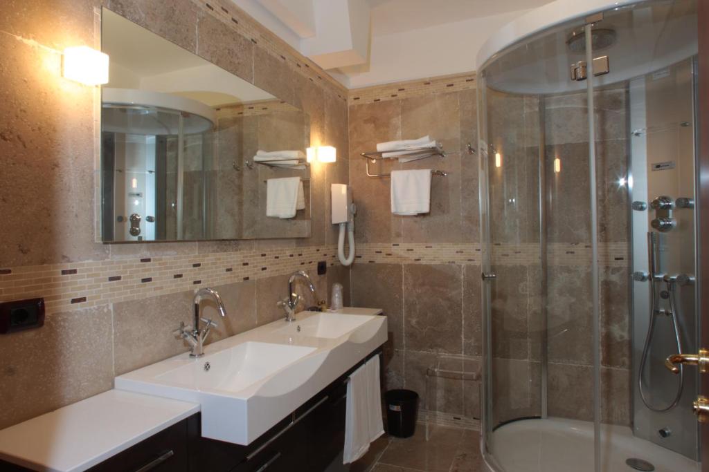 une salle de bain avec deux lavabos et une douche dans l'établissement Hotel Relais dei Normanni, à Monte SantʼAngelo