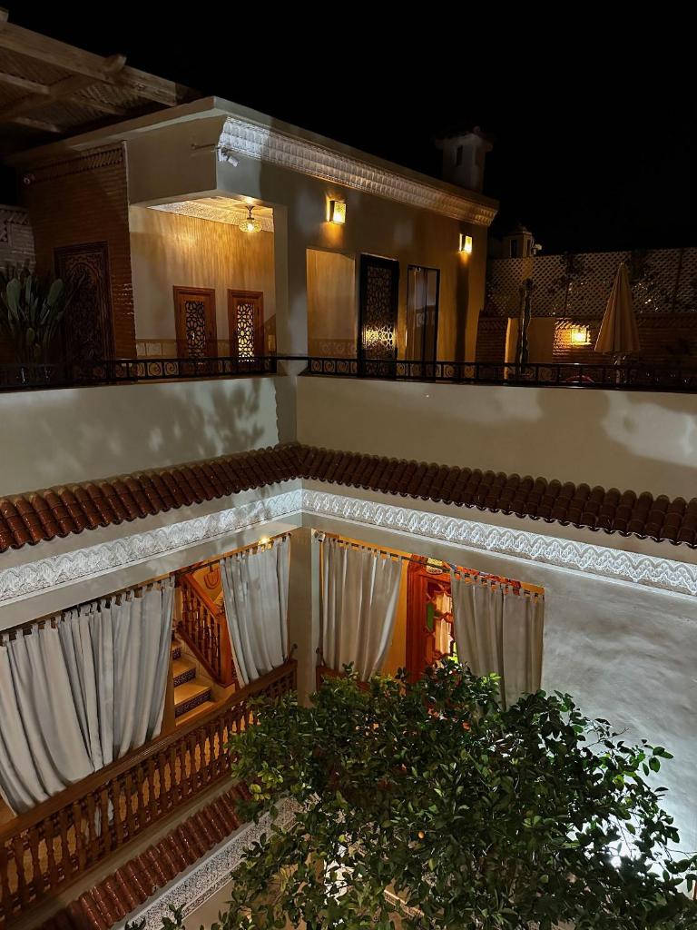 une maison blanche avec une clôture et une terrasse couverte la nuit dans l'établissement RIAD SHAJARA, à Marrakech