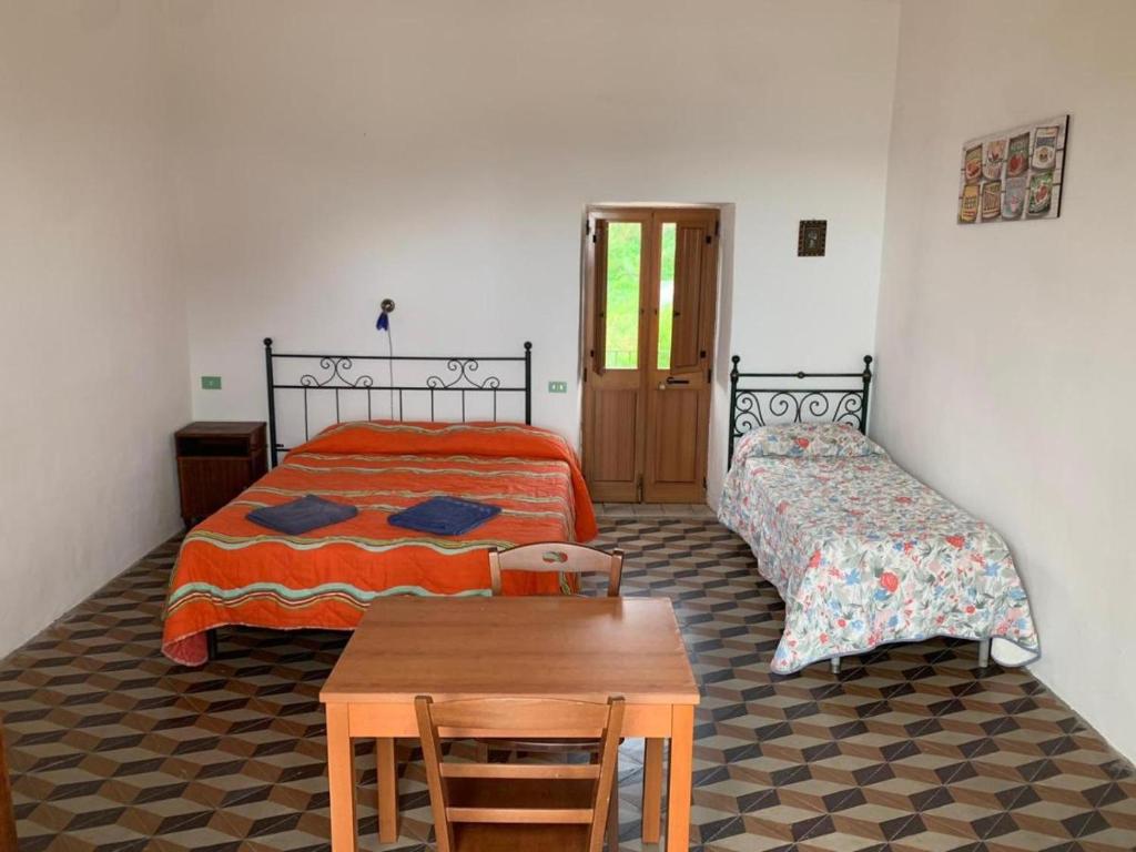 - une chambre avec 2 lits et une table en bois dans l'établissement Case La Pergola, à Stromboli
