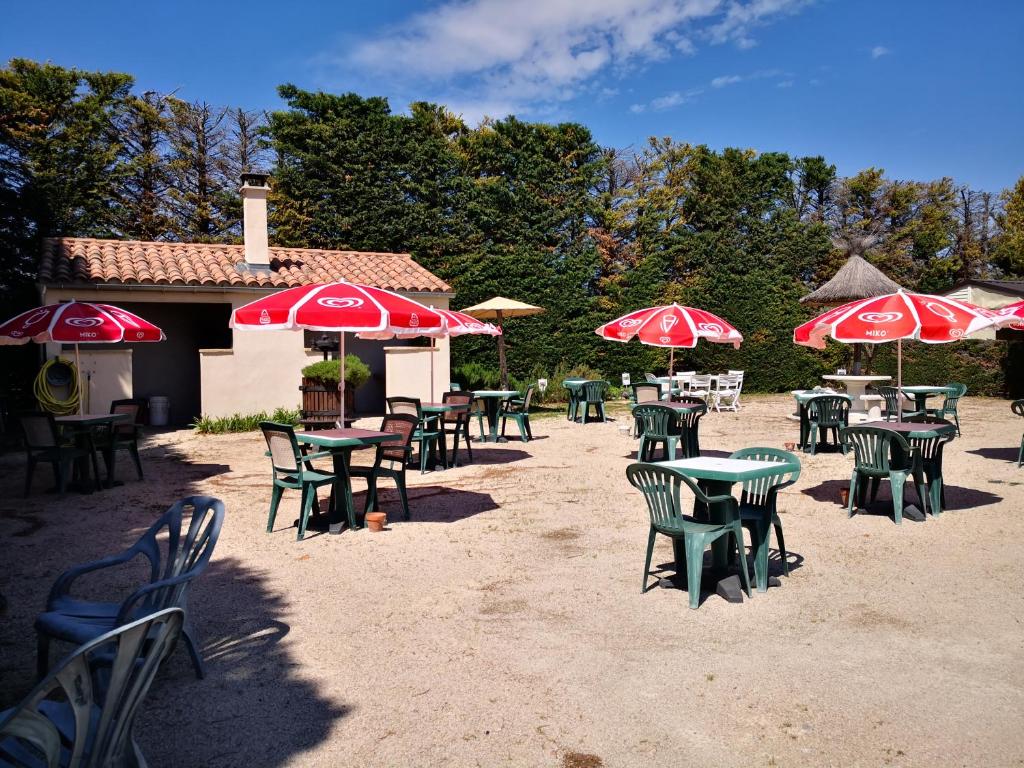 un groupe de tables et de chaises avec parasols dans l'établissement Camping des Favards, à Violès