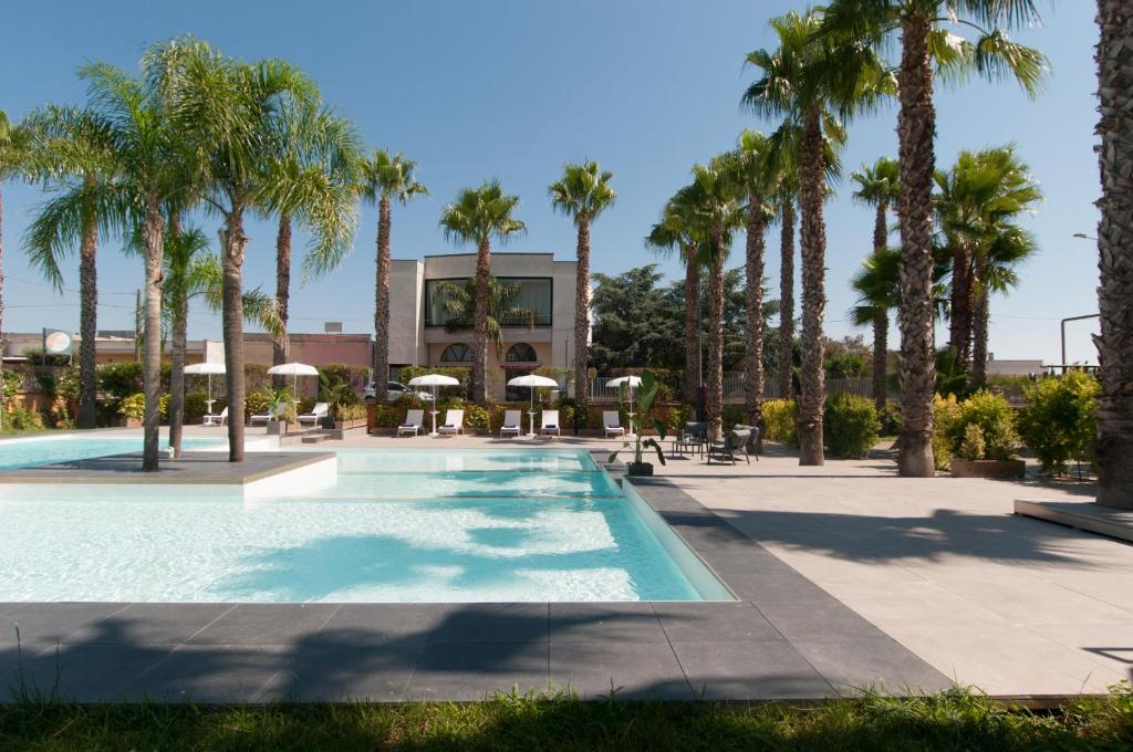 une piscine avec des palmiers et un bâtiment dans l'établissement Sanlu Hotel, à Serrano
