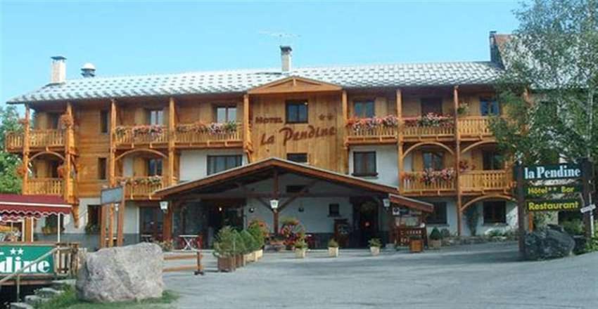 - un grand bâtiment en bois avec un panneau devant dans l'établissement Hôtel Restaurant La Pendine, à Puy-Saint-Vincent