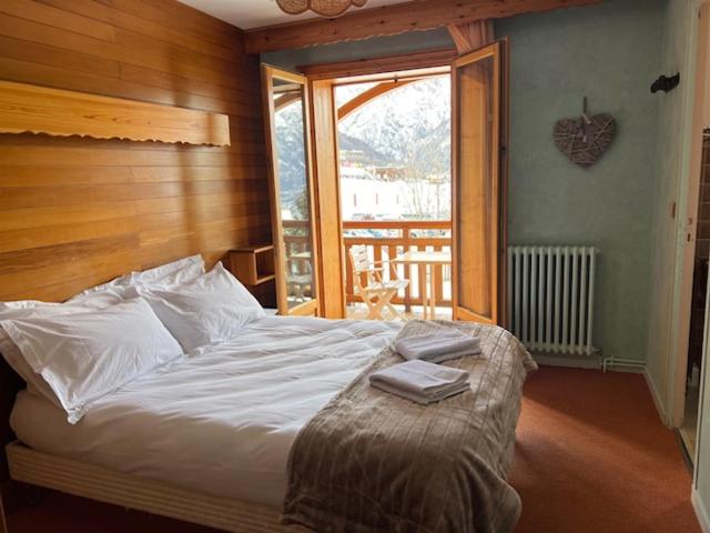 une chambre avec un lit et une grande fenêtre dans l'établissement Hôtel Restaurant La Pendine, à Puy-Saint-Vincent