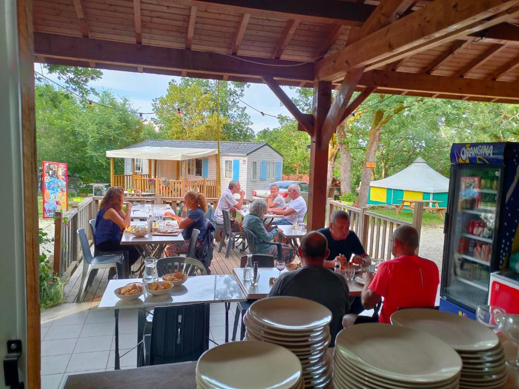 un groupe de personnes assises à table dans un restaurant dans l'établissement CABANE INSOLITE et COCOONING-2personnes-CAMPING LE BEL AIR-LE FRESNE, à Limogne-en-Quercy