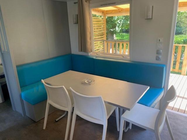 une table et des chaises dans une pièce dotée d'un banc bleu dans l'établissement Mobil home 456, à Ivry-la-Bataille