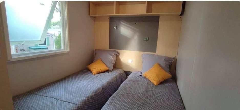 deux lits dans une petite pièce avec une fenêtre dans l'établissement Mobil home Oasis Village 5*, à Puget-sur Argens