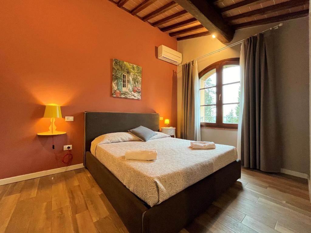 - une chambre avec un lit aux murs orange et une fenêtre dans l'établissement Panoramic Villa Ludovica with private pool - Borgo del Silenzio, à Orciatico