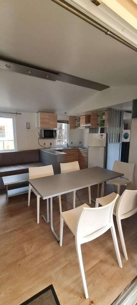 une cuisine avec une table et des chaises dans une pièce dans l'établissement MOBILHOME PREMIUM 3CH 6PERS, à Nans-les-Pins