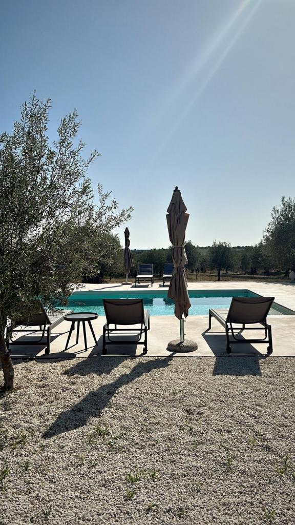 un groupe de tables de pique-nique et un parasol à côté d'une piscine dans l'établissement NOTO country farm house -Tenuta Alessandra, à Noto