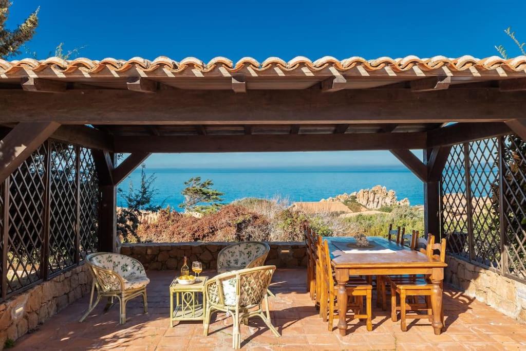 un patio avec une table et des chaises en bois dans l'établissement Villa Carla - Frontsea house with private pool and sauna, à Costa Paradiso