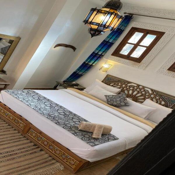une chambre avec un grand lit dans une pièce dans l'établissement Dar Meknes Tresor, à Meknès