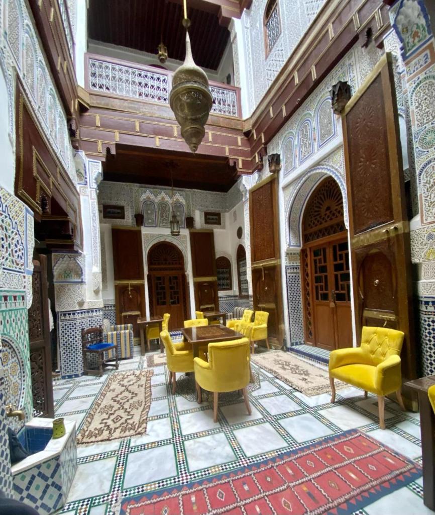 une chambre avec des chaises et des tables jaunes dans un bâtiment dans l'établissement Dar Meknes Tresor, à Meknès