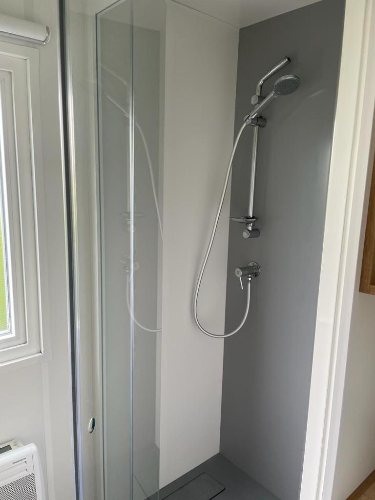 une douche avec une porte vitrée dans une salle de bain dans l'établissement Mobilhome-vue lac-4 étoiles -Lac des Rêves, à Lattes 7 autres photos