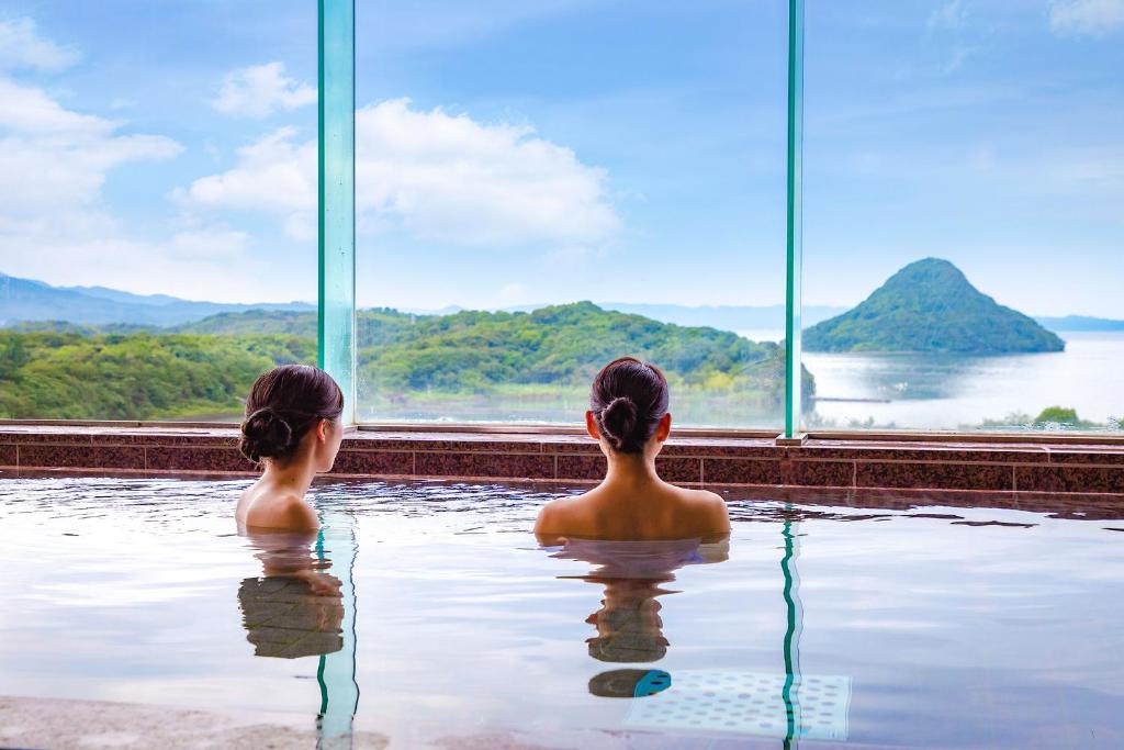 2 filles assises dans une piscine donnant sur l'eau dans l'établissement Ooedo Onsen Monogatari Amakusa Hotel Kameya, à Kami Amakusa