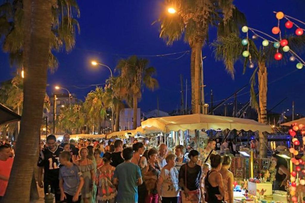 Une foule de gens debout autour d'un marché la nuit dans l'établissement Paradis bleu et ile d'or, à Saint-Raphaël 37 autres photos