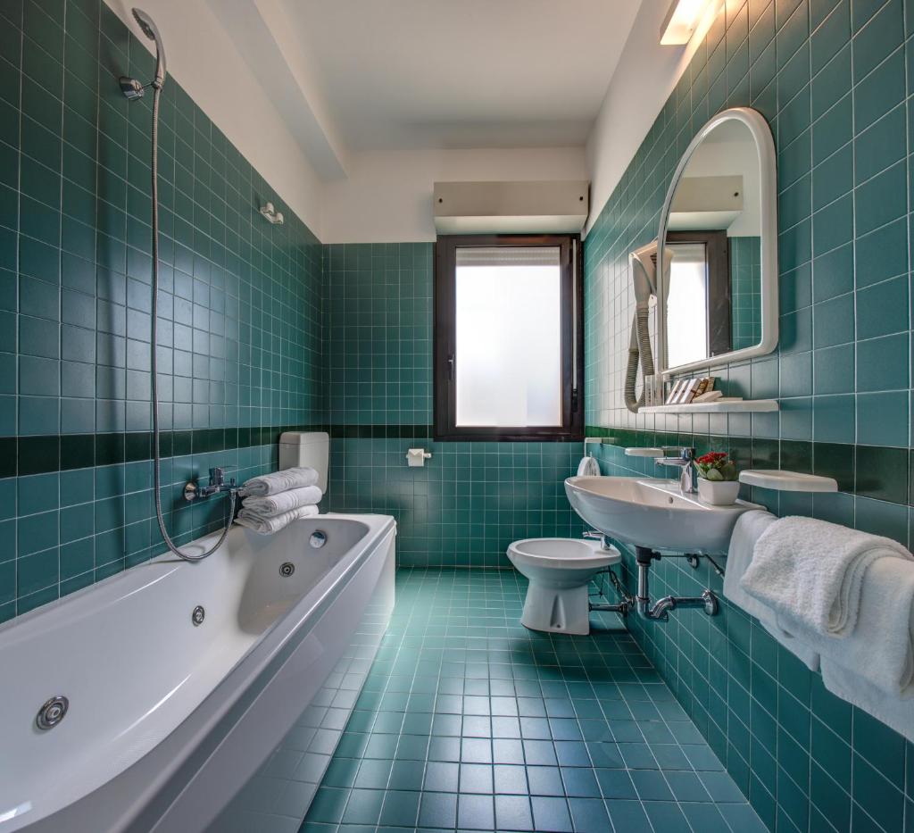 une salle de bain avec du carrelage vert et une baignoire et un lavabo dans l'établissement Hotel Cristallo, à Cattolica 27 autres photos