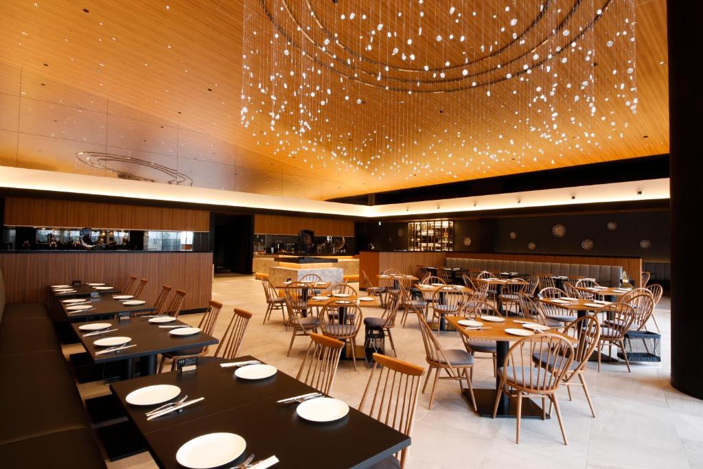 un restaurant avec des tables, des chaises et un lustre dans l'établissement Hida Takayama Onsen Takayama Green Hotel - KEIO GROUP HOTELS -, à Takayama