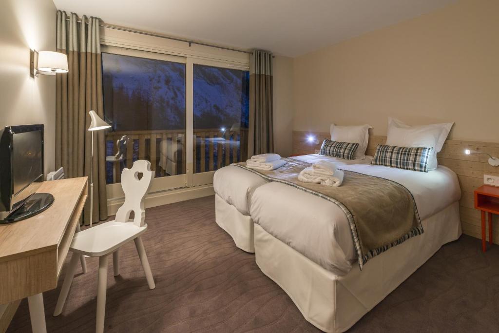 une chambre d'hôtel avec un grand lit et une fenêtre dans l'établissement Les Chalets Du Jardin Alpin, à Val dʼIsère
