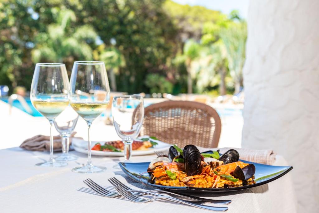 une table avec une assiette de nourriture et des verres à vin dans l'établissement Abamar Hotel, à Santa Margherita di Pula