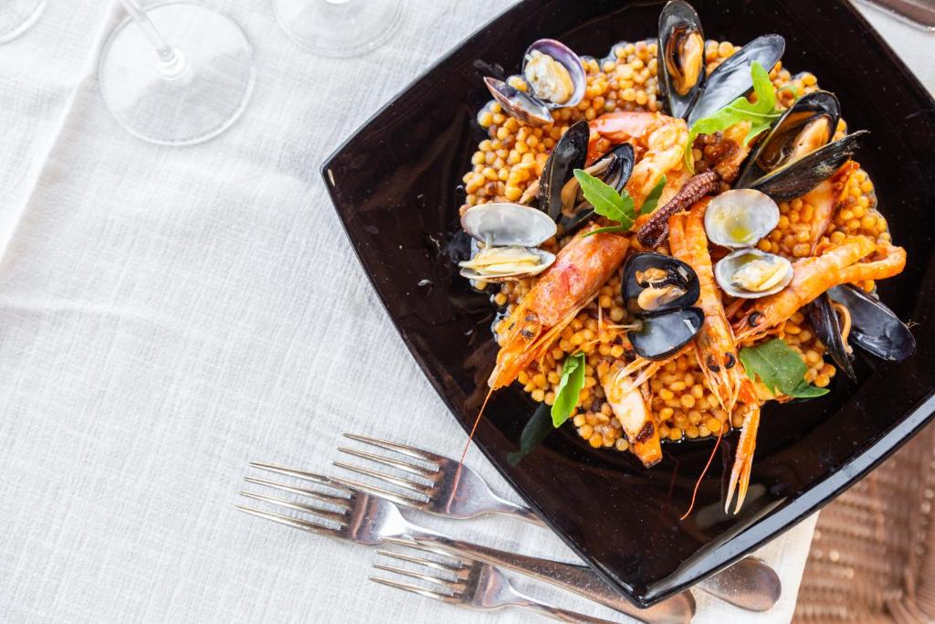 une assiette de nourriture avec des fruits de mer et du maïs sur une table dans l'établissement Abamar Hotel, à Santa Margherita di Pula