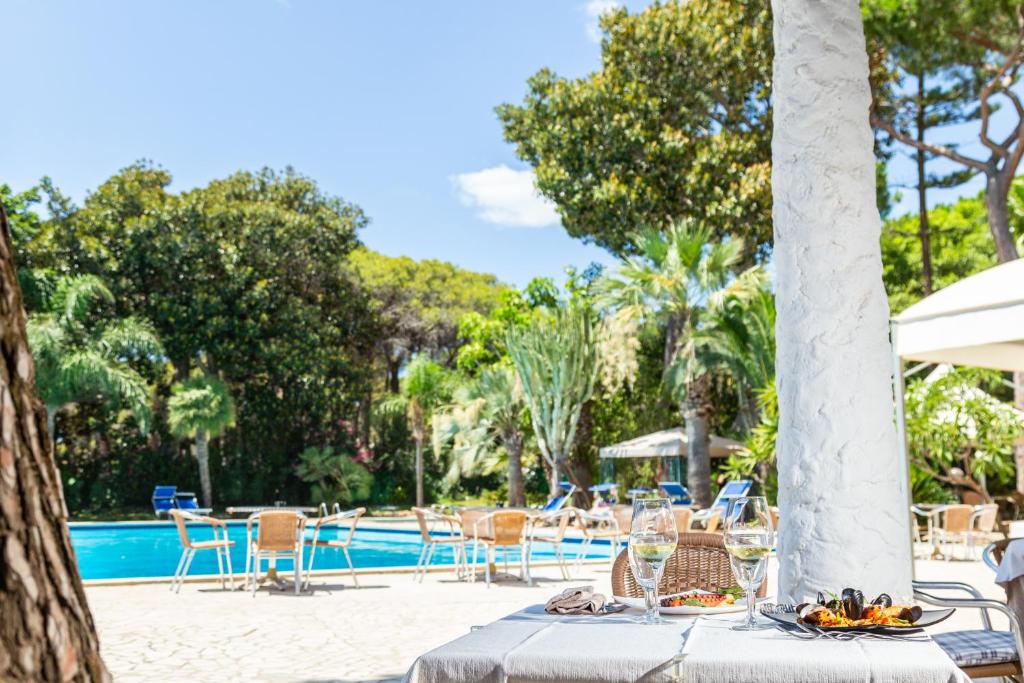 - une table et des chaises au bord de la piscine d'un complexe dans l'établissement Abamar Hotel, à Santa Margherita di Pula