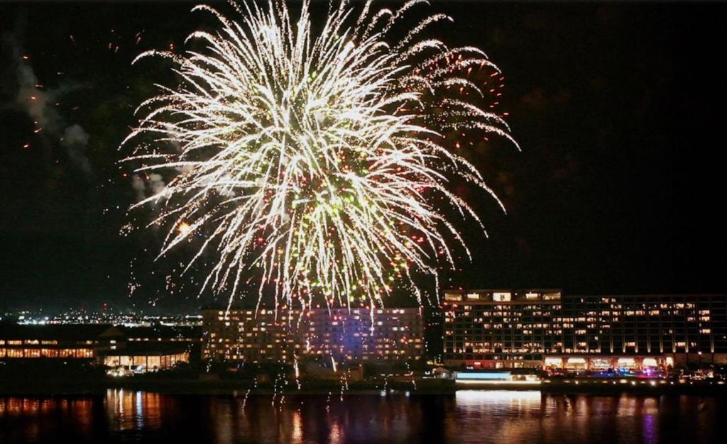 un feu d'artifice au-dessus de l'eau avec une ville dans l'établissement Ryugujo Spa Hotel Mikazuki Fujimitei, à Kisarazu 37 autres photos