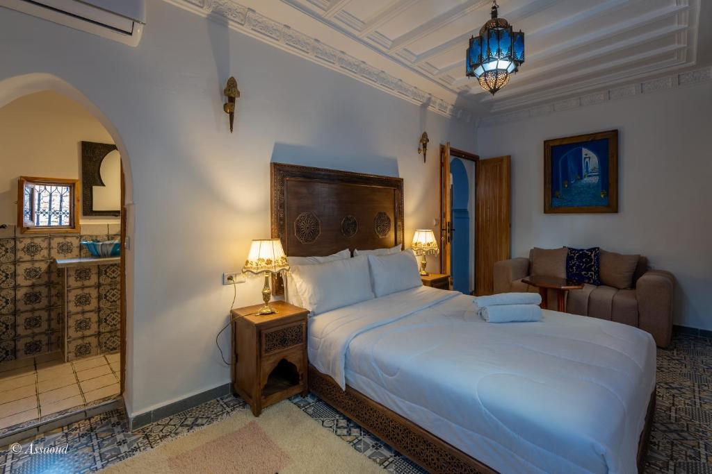 une chambre avec un grand lit blanc et un canapé dans l'établissement Dar Bleumain, à Chefchaouen