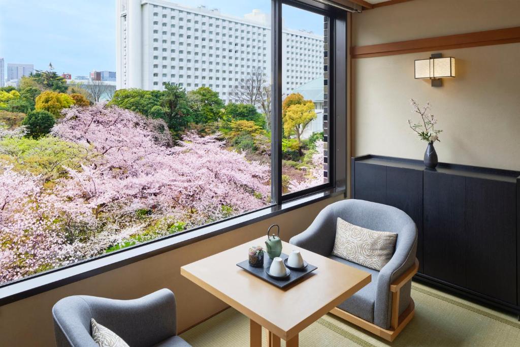une chambre avec deux chaises, une table et une grande fenêtre dans l'établissement Takanawa Hanakohro - in Grand Prince Hotel Takanawa, à Tokyo