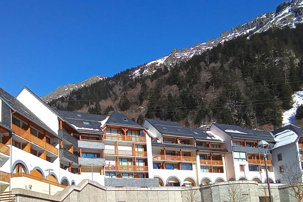 un grand bâtiment avec une montagne en arrière-plan dans l'établissement Appartement chaleureux en cœur de station, à Laruns