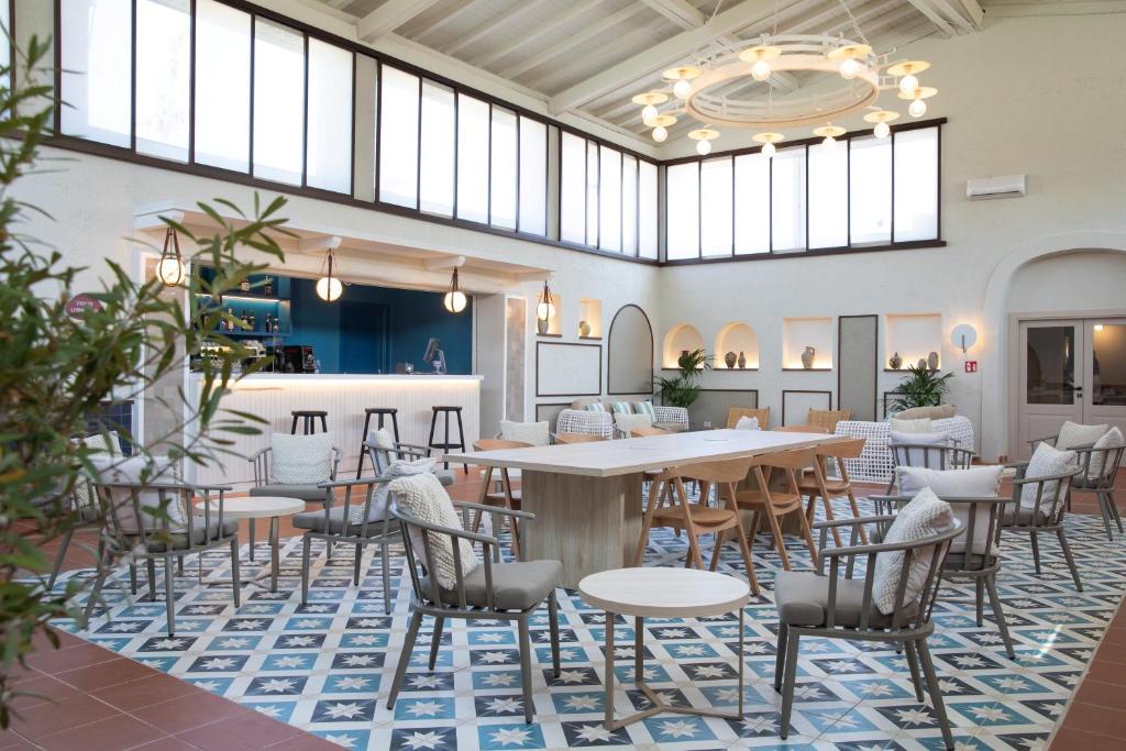 une salle à manger avec tables, chaises et fenêtres dans l'établissement MClub Budoni, à Budoni