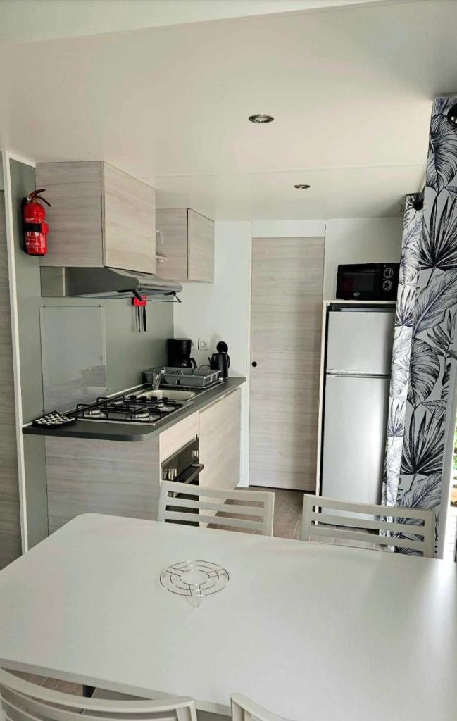 La cuisine est équipée d'un comptoir blanc et d'un réfrigérateur. dans l'établissement Mobile home n°261 2chambres à 2 pas du lac !, à Gastes