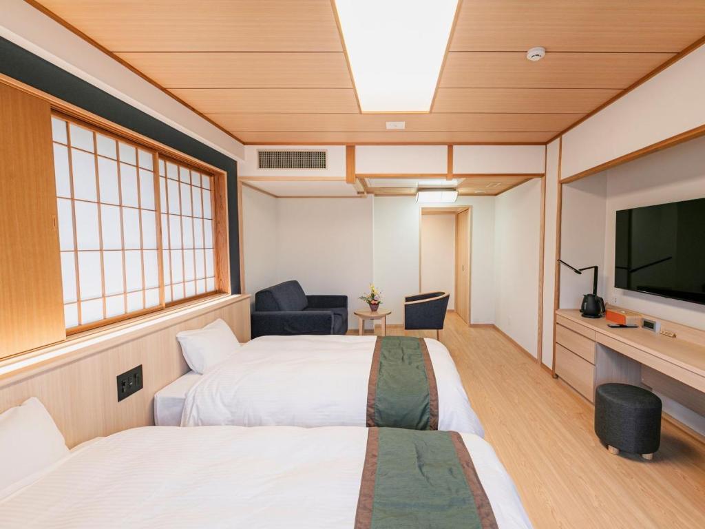 une chambre avec deux lits et une télévision à écran plat dans l'établissement Ureshino Motoyu, à Ureshino