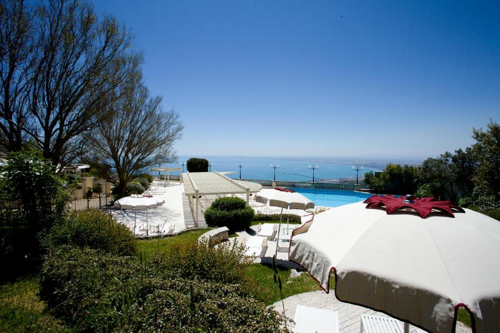 - un grand parasol blanc à côté de la piscine dans l'établissement Hotel Relais dei Normanni, à Monte SantʼAngelo