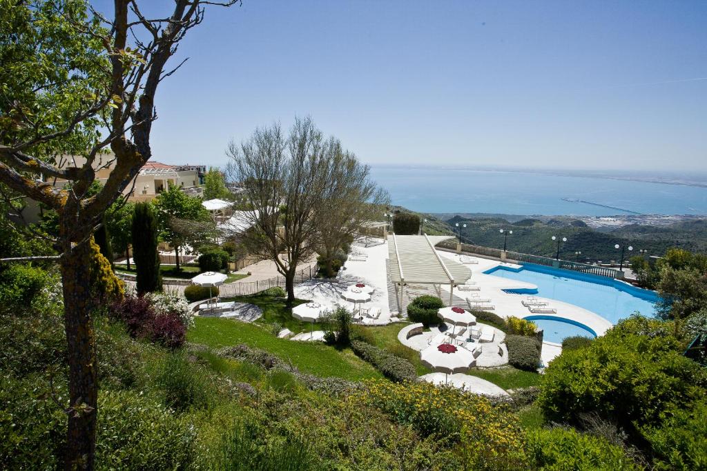 un complexe avec une piscine et l'océan dans l'établissement Hotel Relais dei Normanni, à Monte SantʼAngelo
