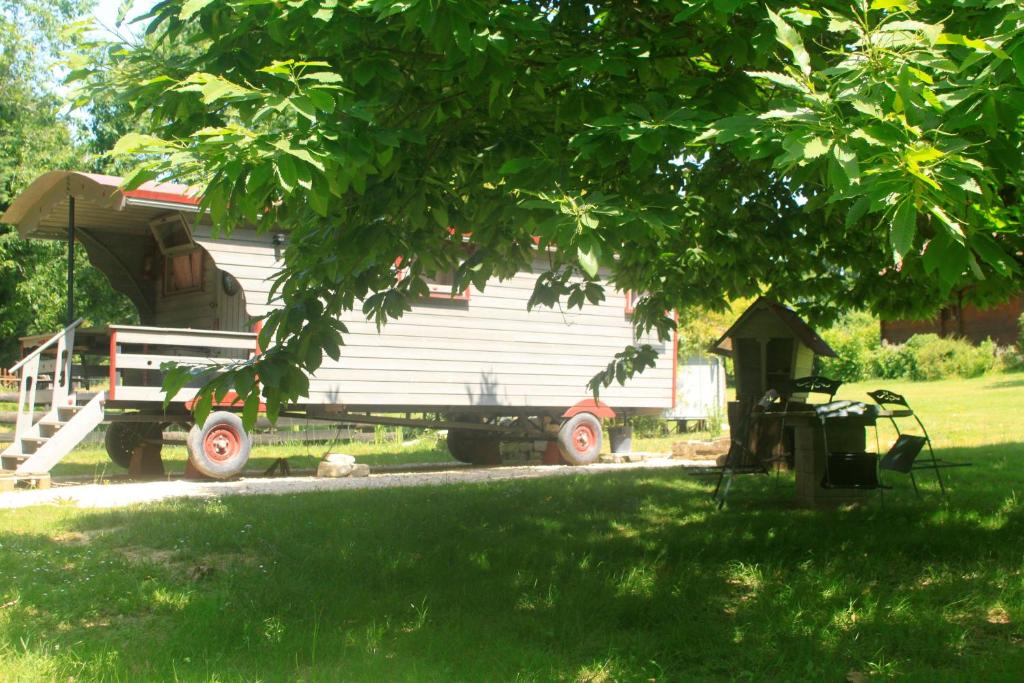 une remorque avec une maison assise dans une cour dans l'établissement Belle Roulotte unique en pleine campagne Au Jardin de la Vouivre, à Saint-Vincent-en-Bresse