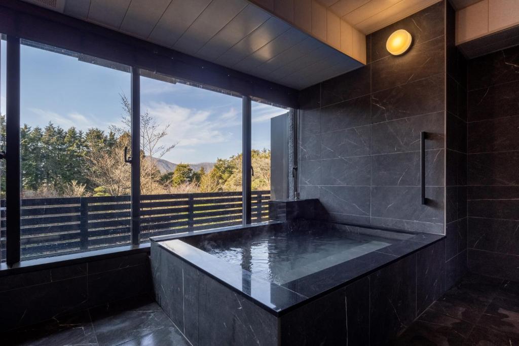 La salle de bains est pourvue d'une grande baignoire et d'une grande fenêtre. dans l'établissement Sengokubara COCON, à Hakone
