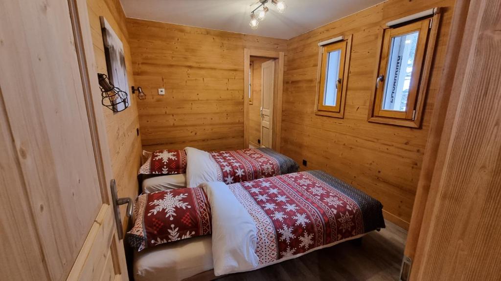 - 2 lits dans une chambre dotée de murs en bois et de fenêtres dans l'établissement L'Étoile du Linga, à Châtel